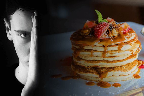 Man reviews food intolerance test while scowling at pancakes.